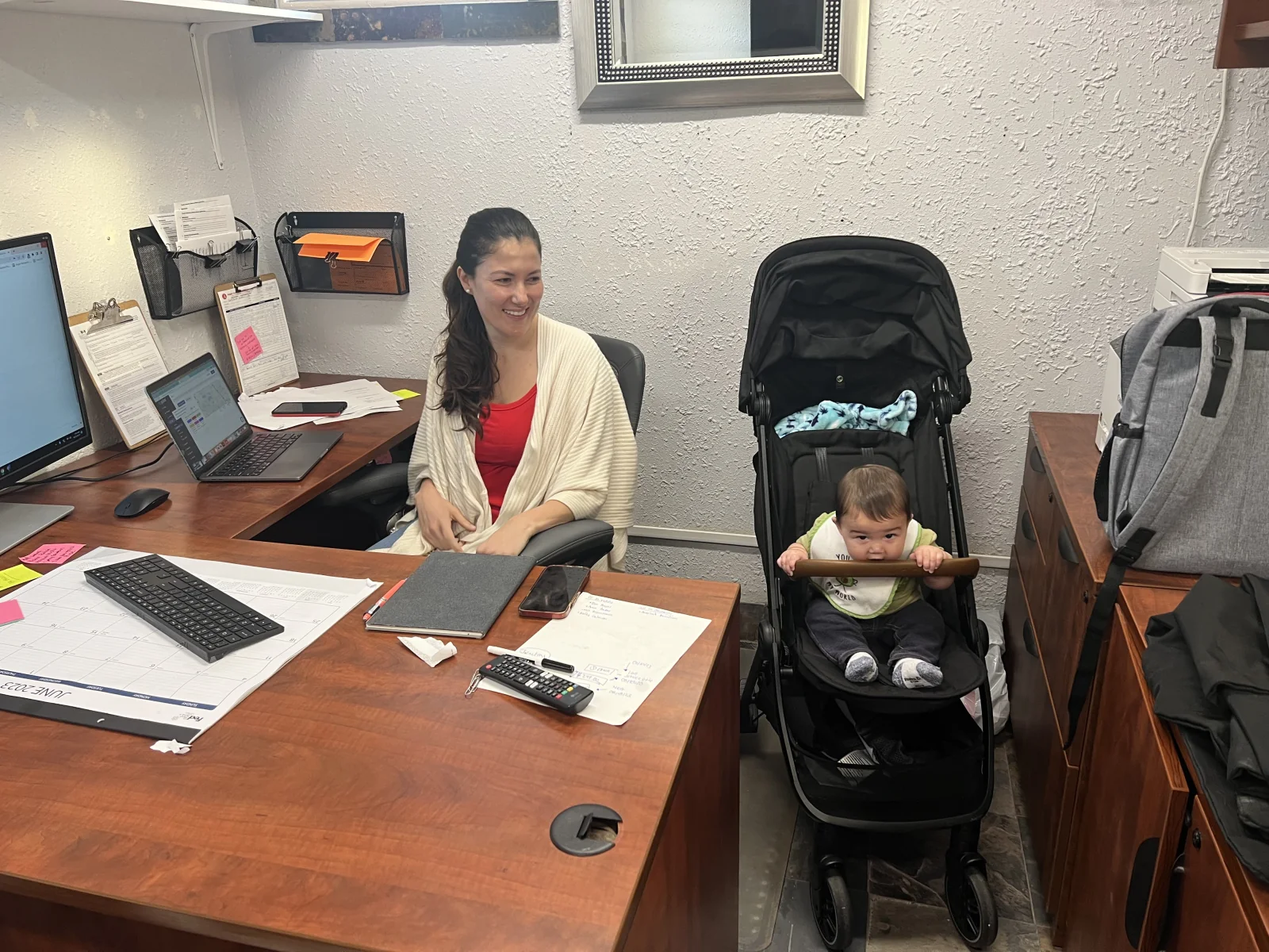 Andrea working at her desk with her baby beside her in a stroller
